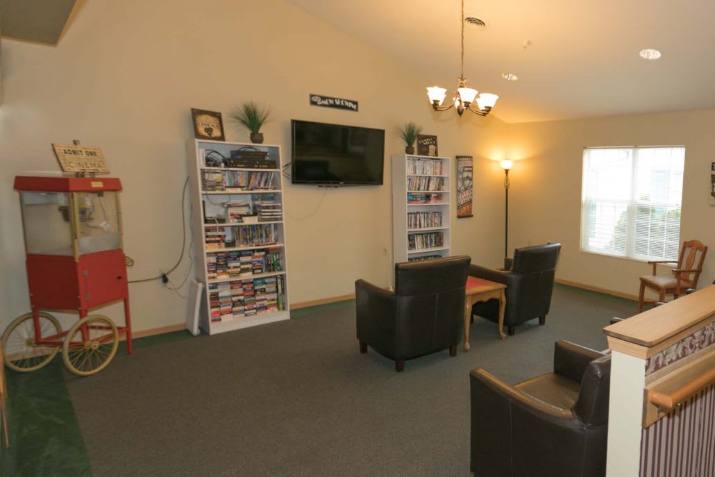 A cozy living room with a TV, bookshelves, and comfortable seating.
