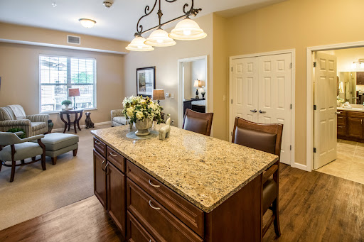A cozy kitchen space featuring a granite island, wooden seating, and warm lighting.