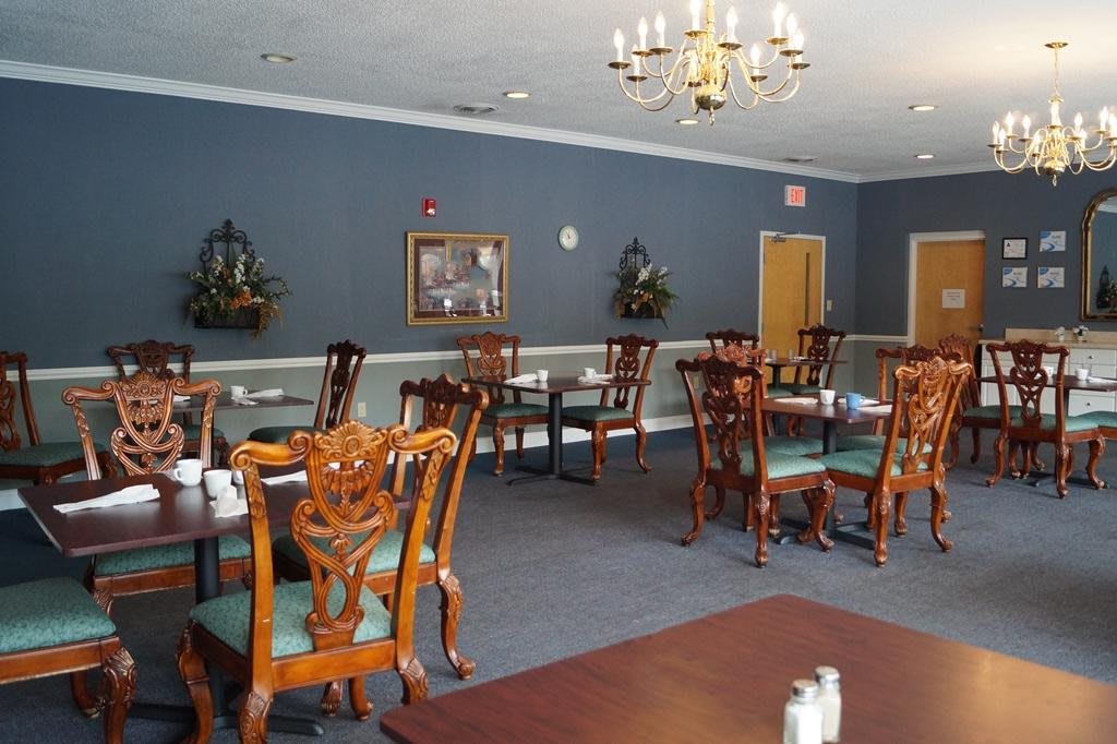 An elegant dining room with wooden tables and chairs, adorned with a chandelier and blue walls.