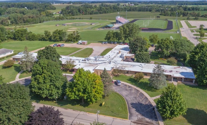 An aerial view of a building surrounded by greenery and fields.