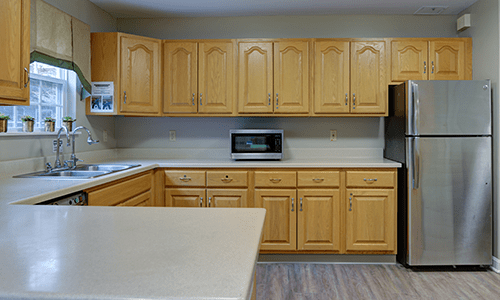A kitchen featuring wooden cabinets and a countertop with a microwave.