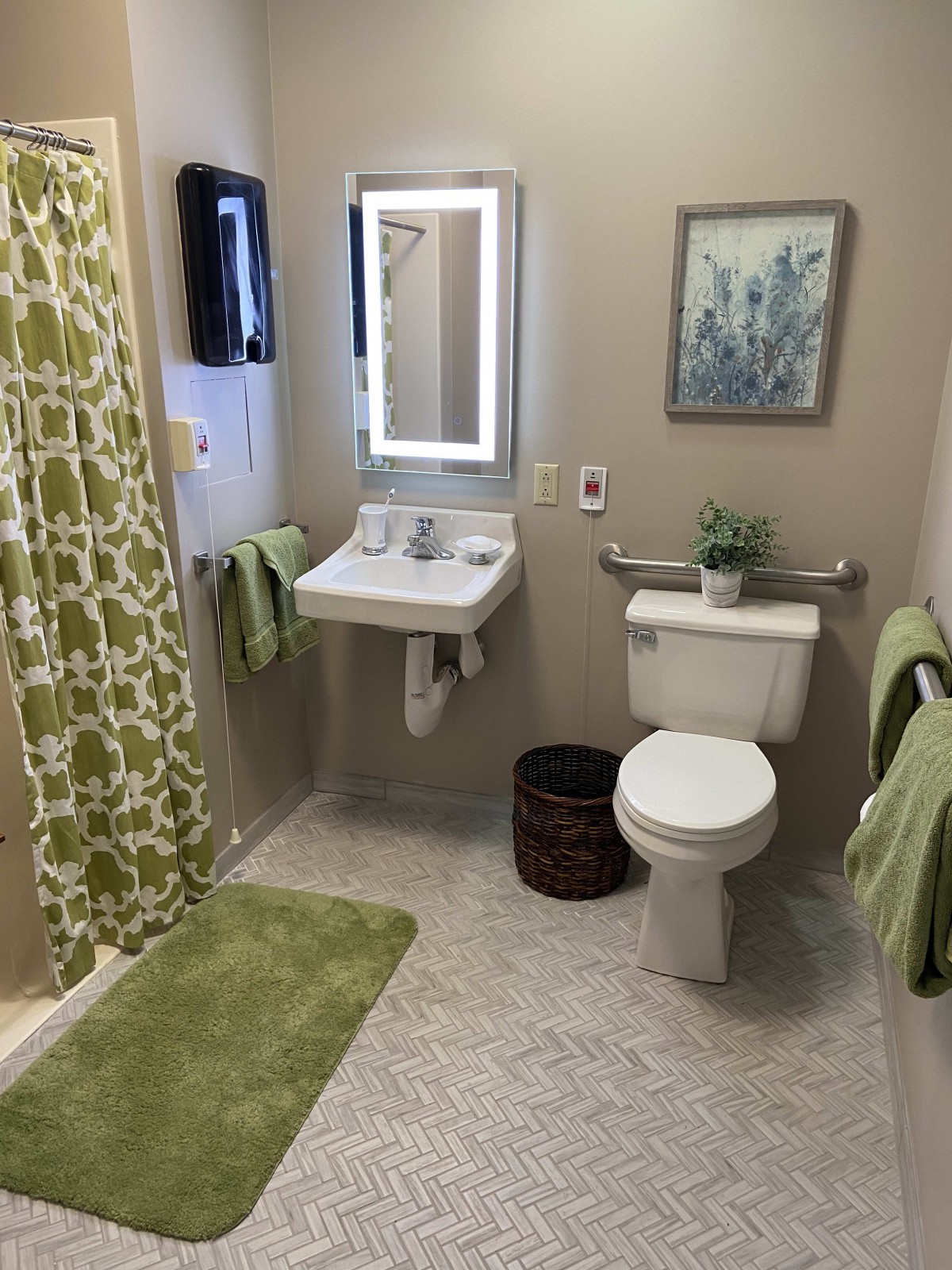 A neatly organized bathroom with green accents and a decorative plant.