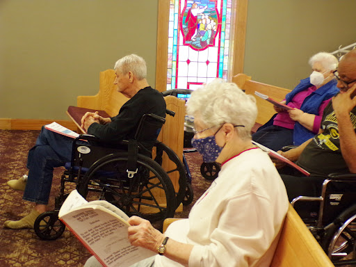 Elderly individuals participating in a communal reading during a religious service.