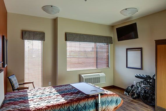 A hospital room featuring a bed, television, and medical equipment.