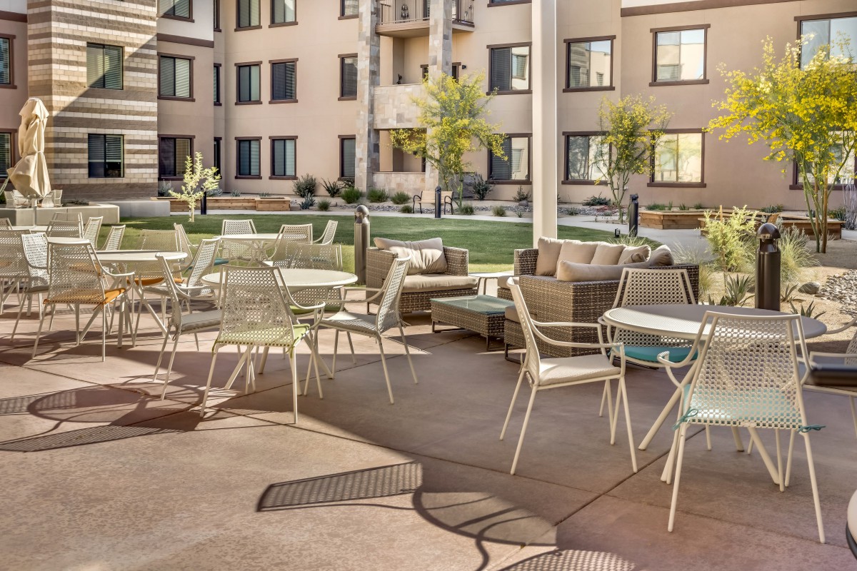 A modern outdoor seating area with tables and chairs in an apartment complex.