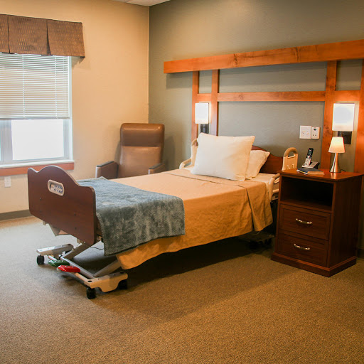 A cozy hospital room featuring a bed, nightstand, and comfortable seating.