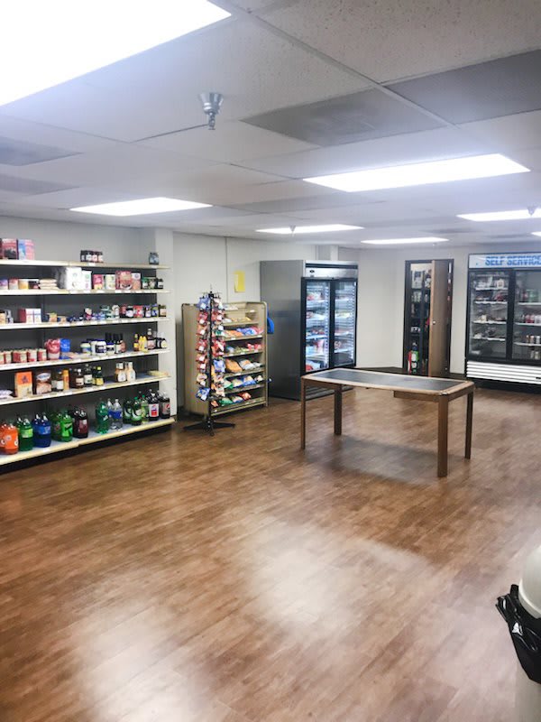 A small grocery store with shelves and refrigerators.