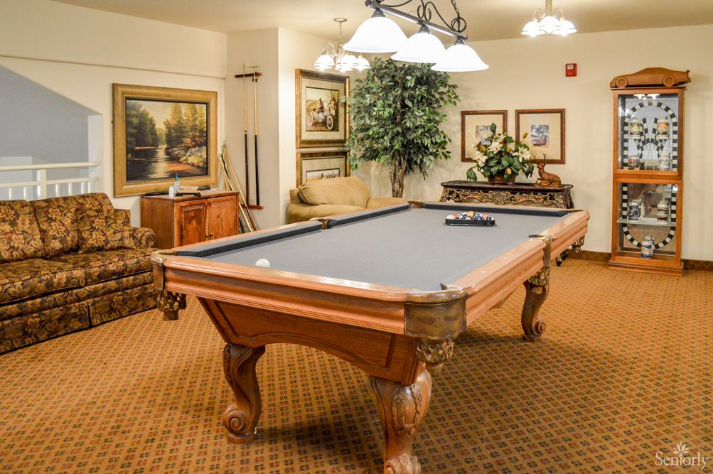 A cozy game room featuring a classic pool table, complete with elegant decor and artwork.