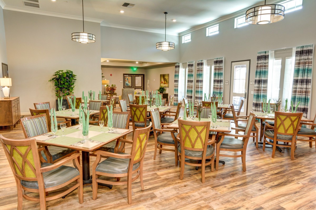 A spacious and bright dining area with neatly arranged tables and chairs, featuring decorative elements and modern lighting.