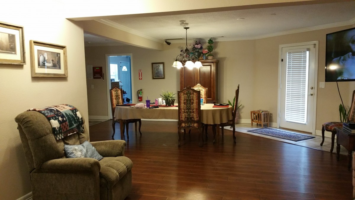 A cozy dining room with a wooden table and chairs, a chandelier, and hardwood flooring.