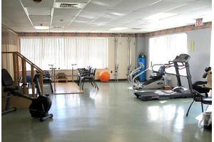A well-lit gym with various fitness equipment including treadmills, exercise bikes, and an exercise ball.