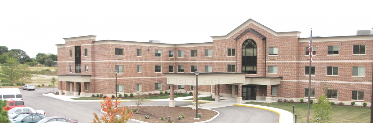 A brick building with multiple windows and a covered entrance.