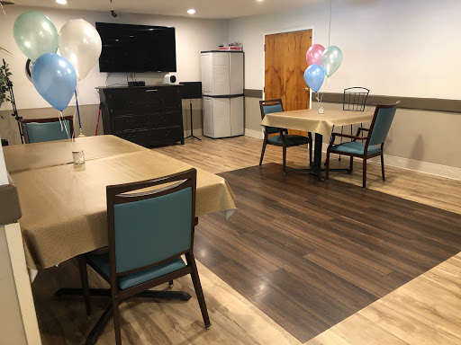 A cozy dining area with tables and chairs, decorated with balloons, featuring a television and a refrigerator in the background.