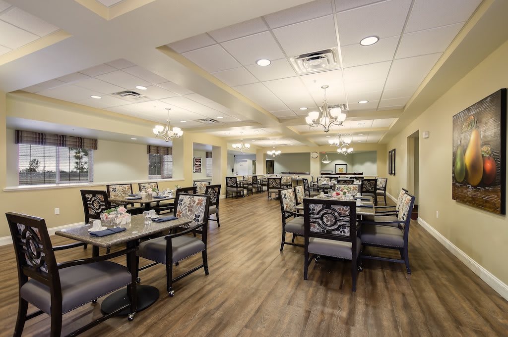 A spacious dining area with elegant chandeliers and neatly arranged tables and chairs.