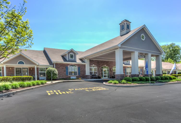 A building with a grand entrance and well-maintained landscaping under a clear blue sky.