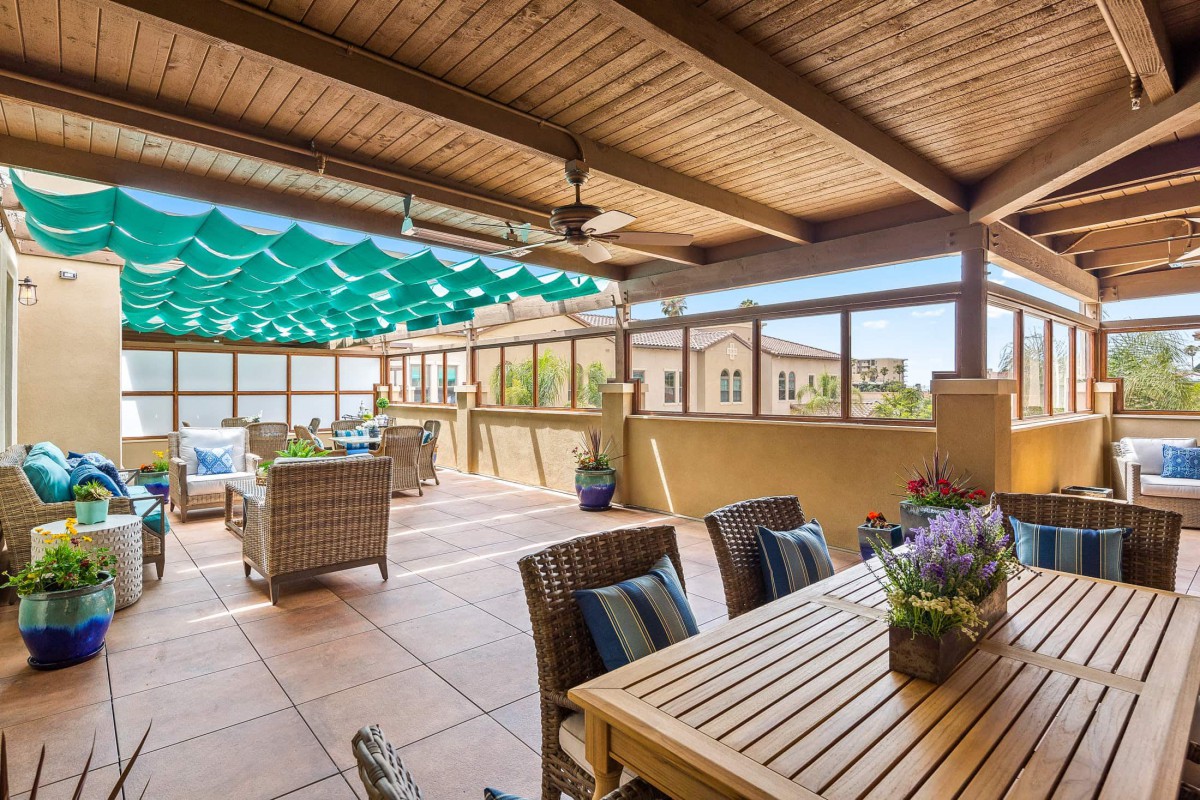 A cozy outdoor patio with a wooden table and comfortable seating, featuring a sunshade for a relaxing ambiance.