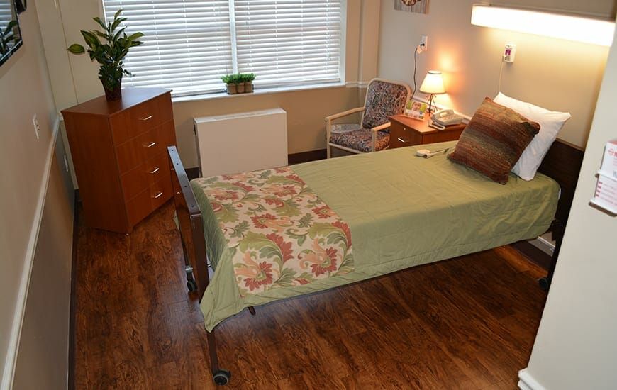 A neatly arranged bedroom with a single bed, bedside table, and a lamp.