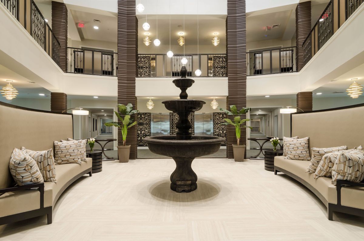 A luxurious lobby interior featuring a central fountain, elegant seating areas, and decorative plants.