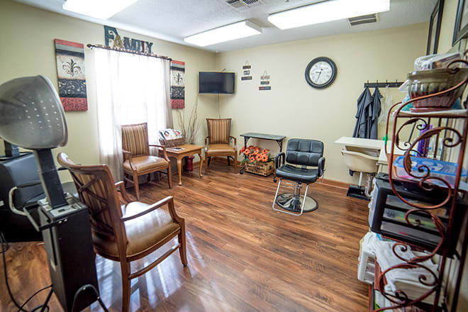 A cozy hair salon waiting area with wooden floors and a variety of chairs.