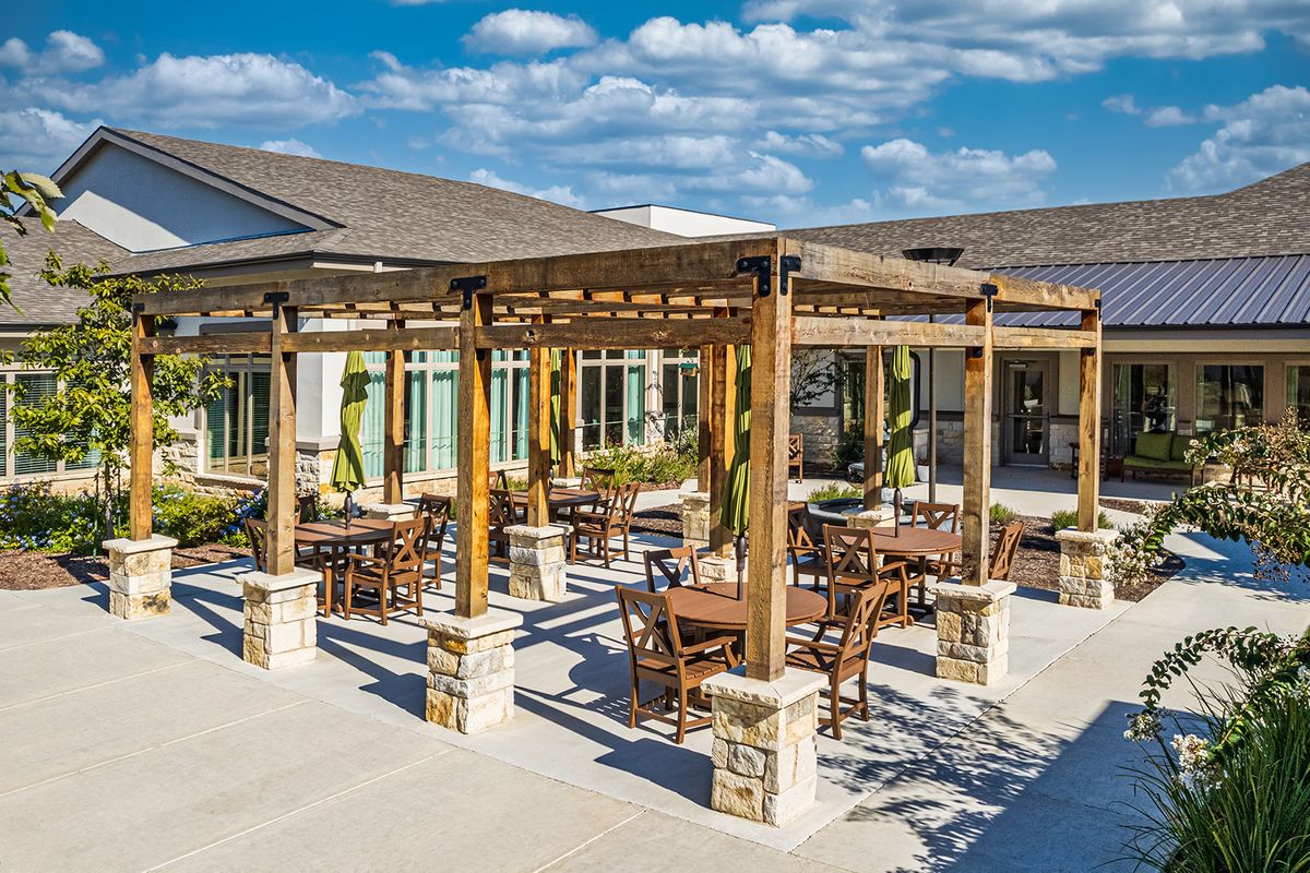 An outdoor seating area with a wooden pergola and patio furniture under a clear blue sky.