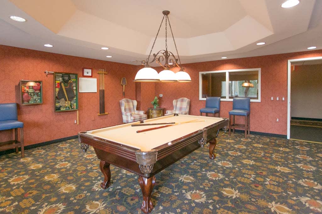A cozy billiard room featuring a pool table, comfortable seating, and warm lighting.