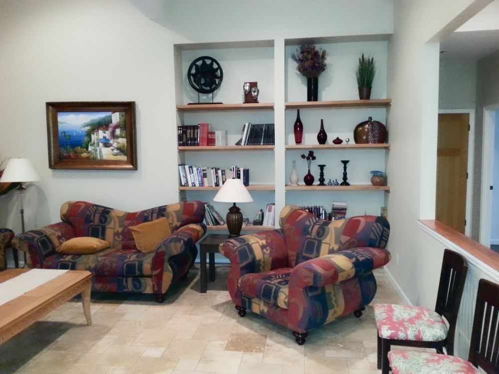 A cozy living room with colorful furniture and decorative shelves.