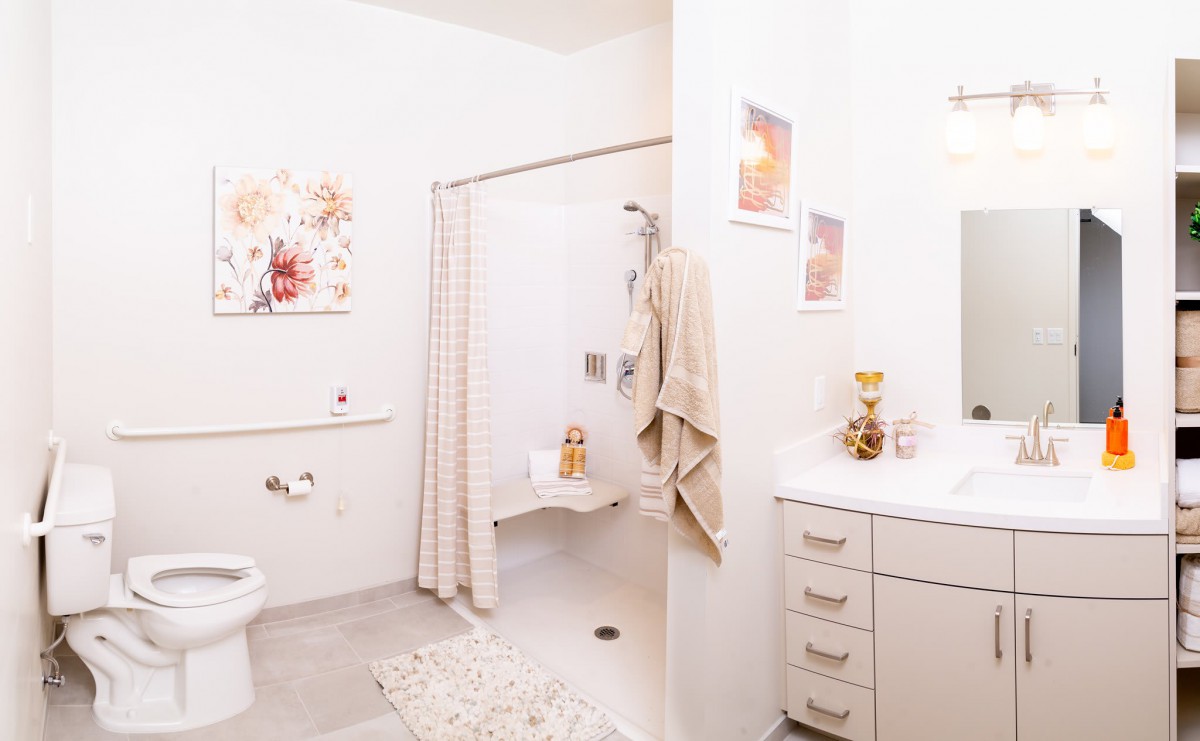 A bright and clean bathroom with modern decor, featuring a shower, vanity, and wall artwork.