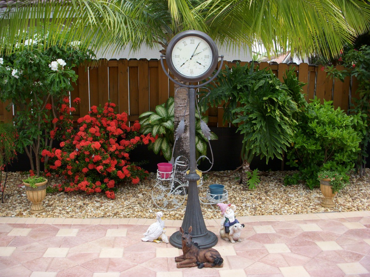 An ornate garden clock surrounded by lush greenery and pigeons.