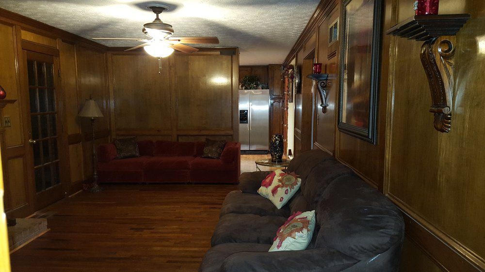 A cozy living room with wood paneling and comfortable sofas.