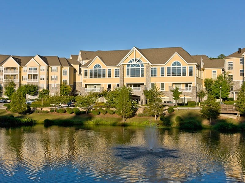A residential building with a scenic lake view reflecting the clear blue sky.