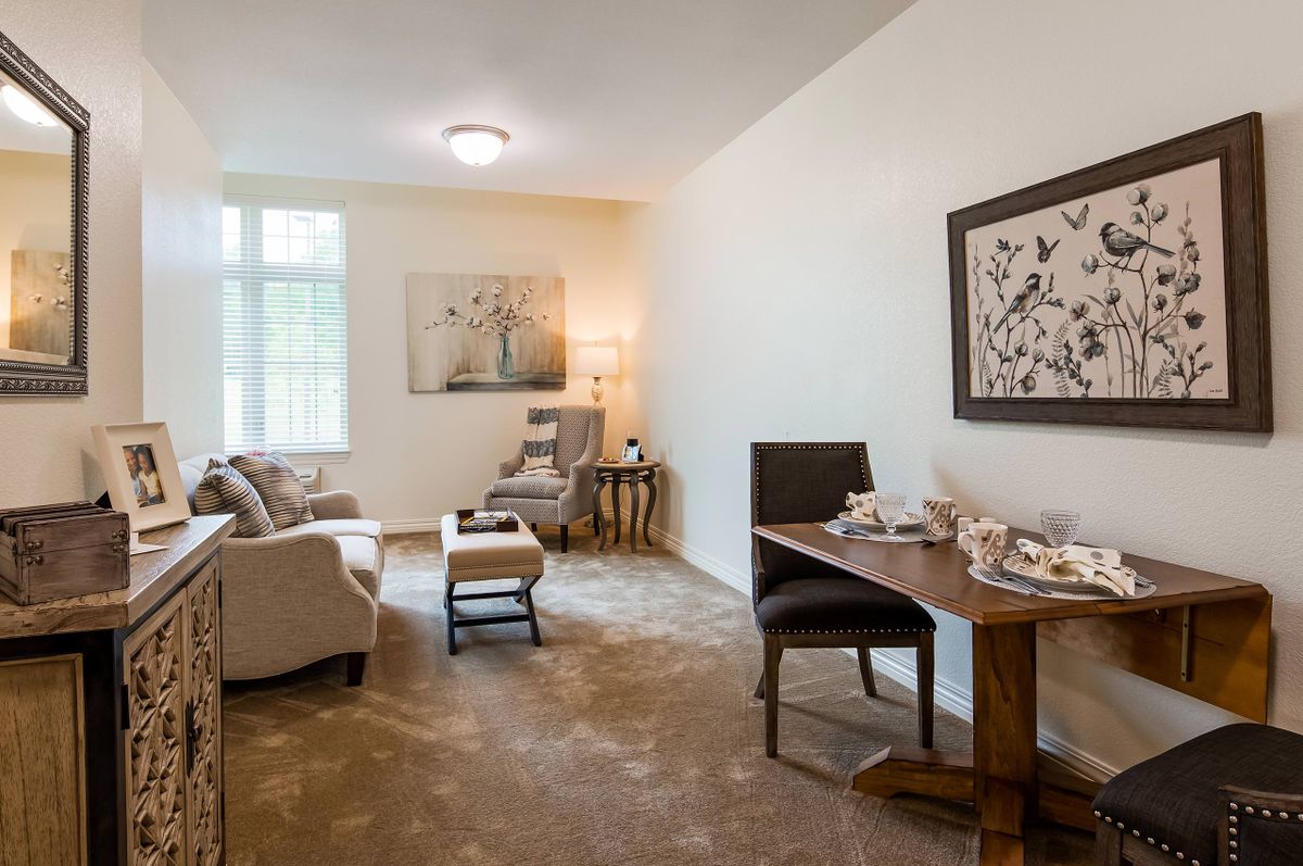 A cozy living room with a comfortable sofa, artwork on the walls, and natural light streaming through the windows.