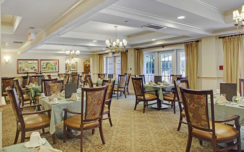 An elegant dining room with neatly set tables and classic chandeliers.