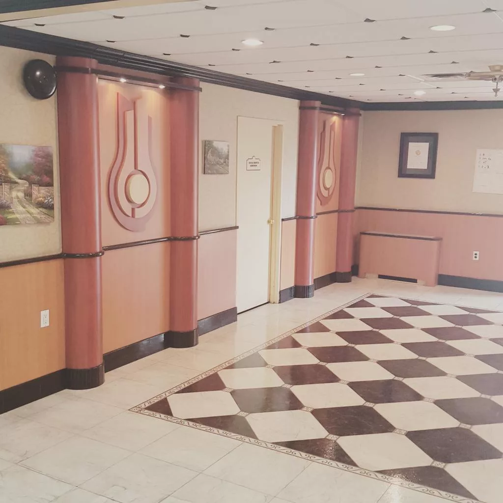 An interior hallway with checkered flooring and decorative wall elements.
