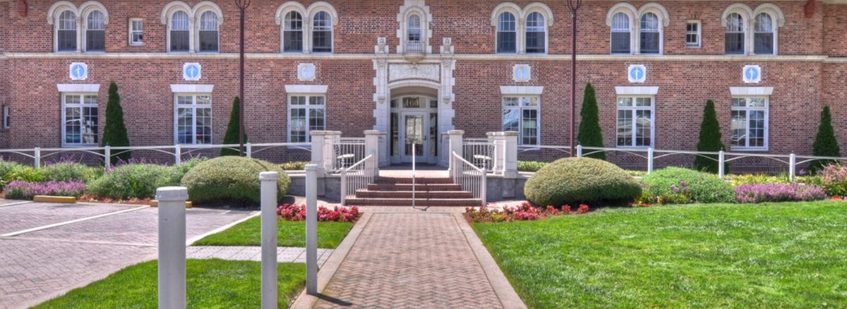 A symmetrical brick building with a central entrance and well-maintained landscaping.