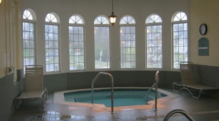 A serene indoor spa pool with large arched windows providing natural light.