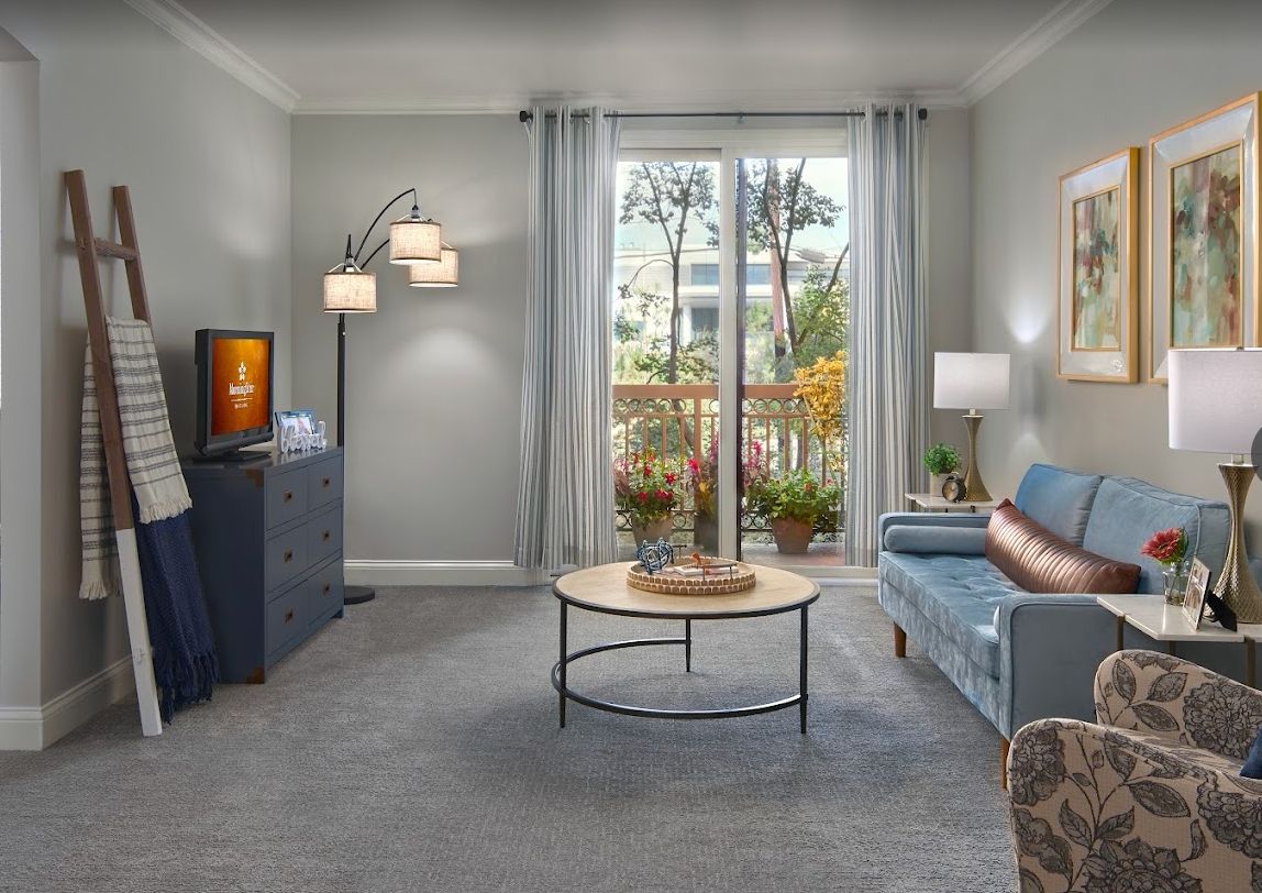 A cozy living room with modern decor, featuring a comfortable sofa, a round coffee table, and a large window letting in natural light.