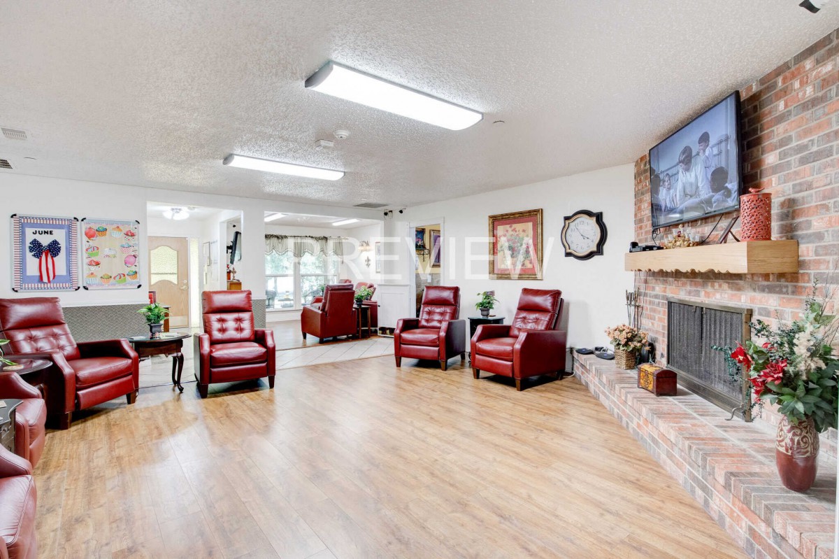 A spacious living room with red chairs, a fireplace, and wooden flooring.