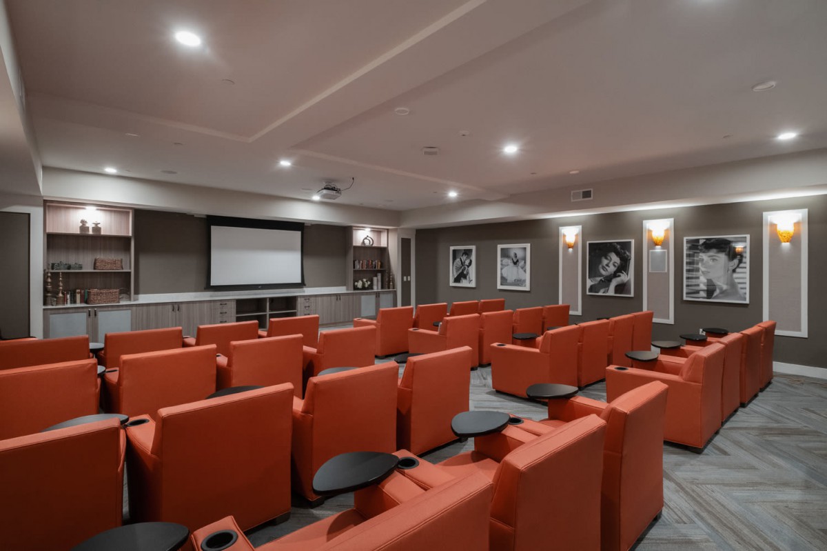 A cozy home theater room with orange seating and a large screen.