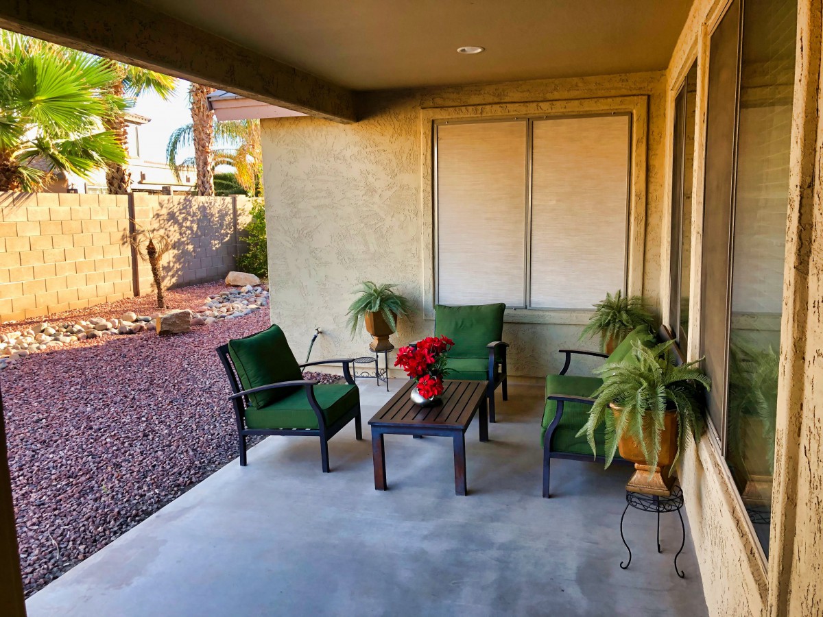 Cozy patio with chairs, a table, and potted plants.