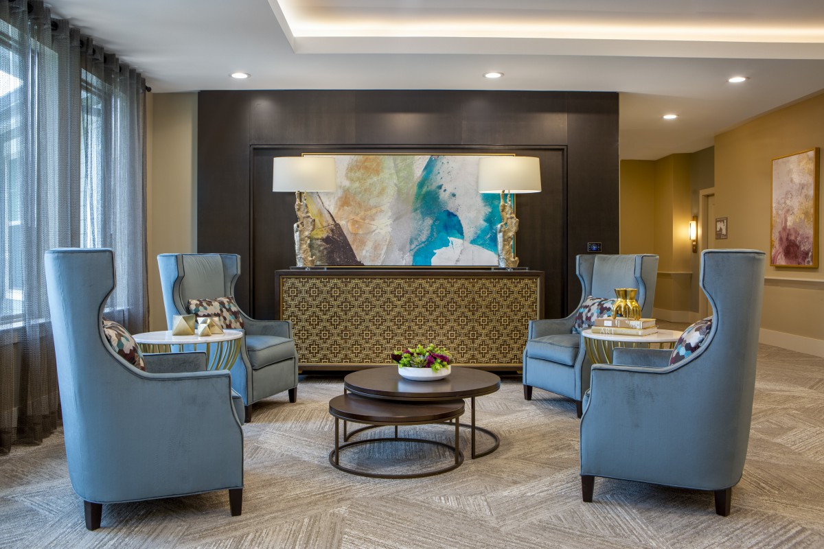 A modern living room with elegant armchairs, a central coffee table, and colorful artwork on the wall.
