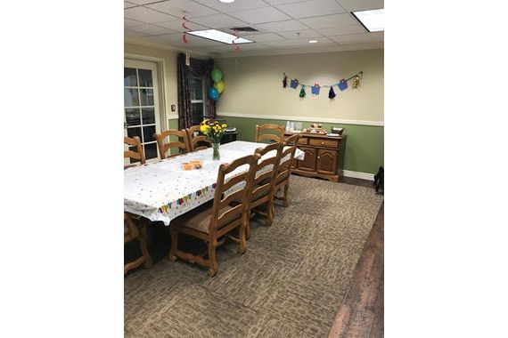 A decorated dining room with a large table, chairs, and festive decorations.