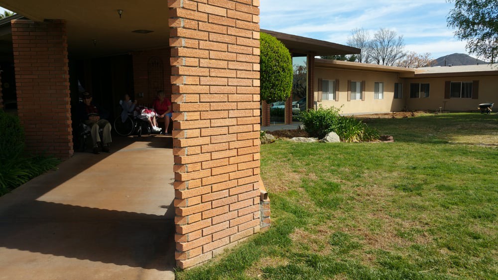 A sunny view of a brick residential building with a well-kept garden and lawn.