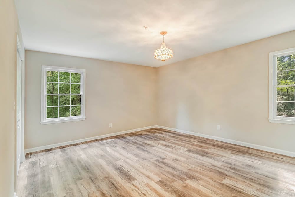 A bright, empty room with hardwood flooring and a window.