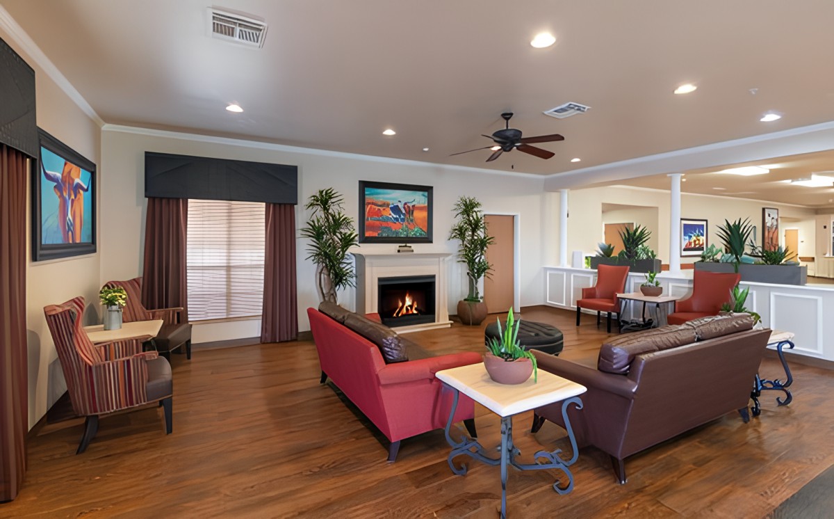 A cozy living room featuring a fireplace, red sofas, and wooden flooring with decorative plants and artwork.