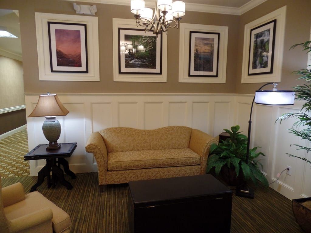 A cozy living room with a sofa, lamp, and framed artwork on the walls.
