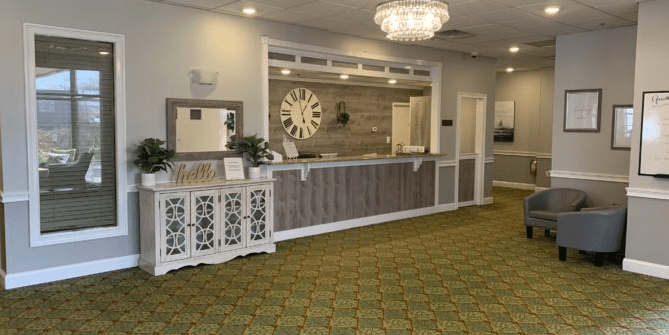A warmly lit reception area featuring a large clock and elegant chandelier.