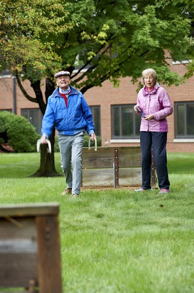 An elderly couple enjoying an outdoor lawn game together.