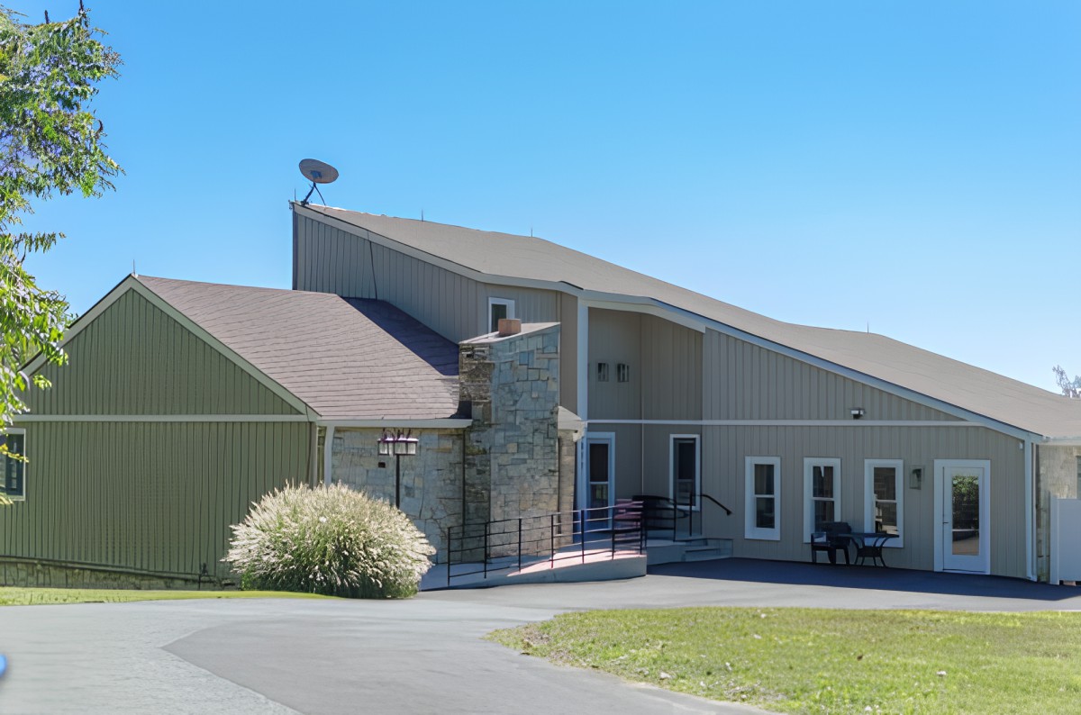 A modern suburban building with a sloped roof and a stone facade on a clear day.