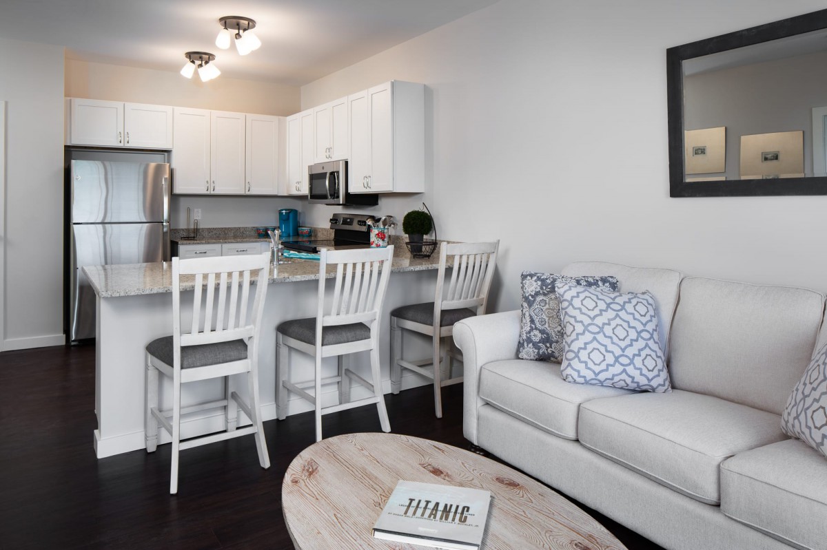 A modern open-concept living room and kitchen area with white furniture and cozy decor.