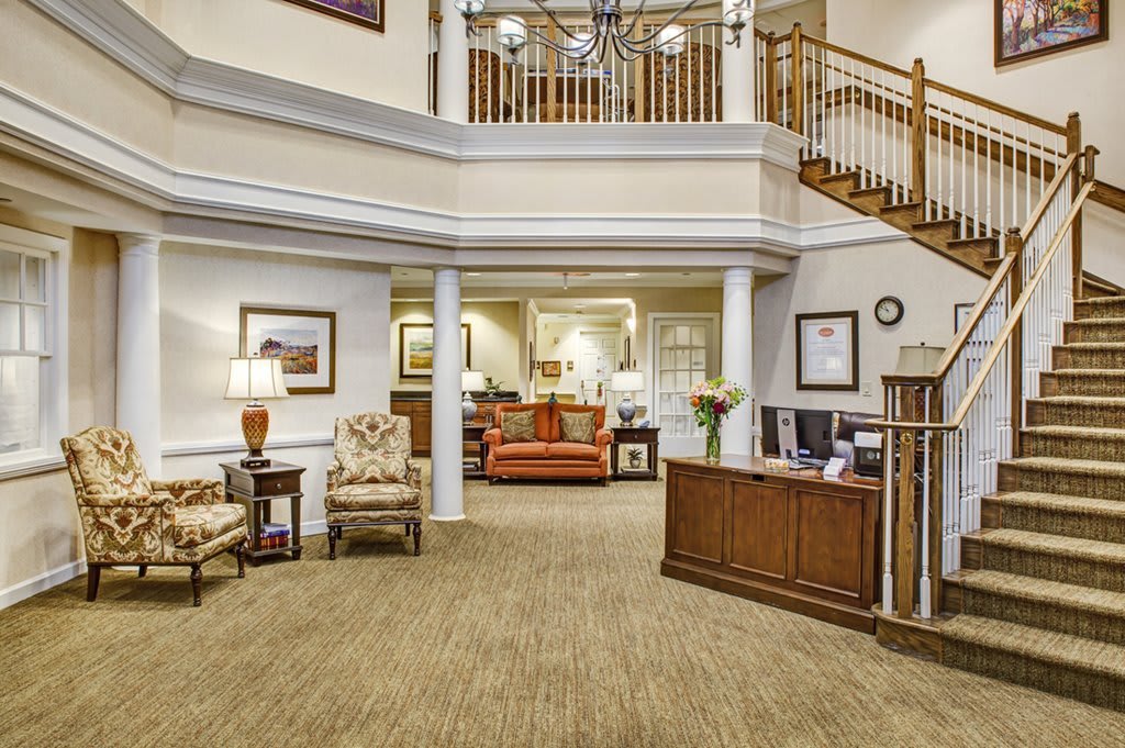 A spacious and elegantly designed lobby with a reception desk, comfortable seating, and a staircase leading to the upper floor.